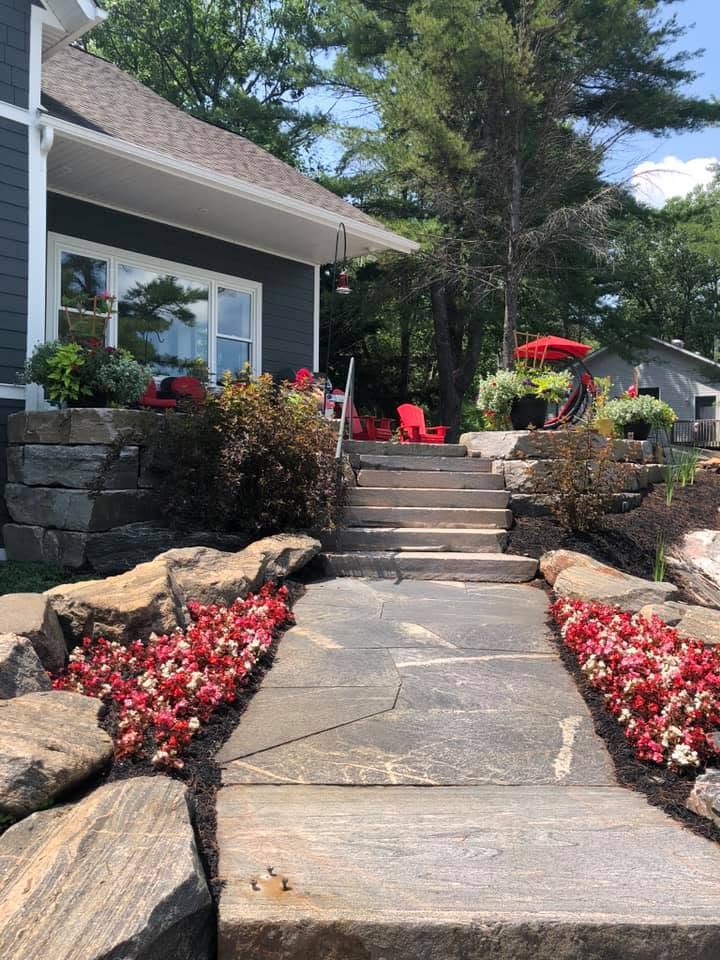 Natural flagstone walkway with stone steps, granite retaining walls and flower beds leading to a Muskoka home